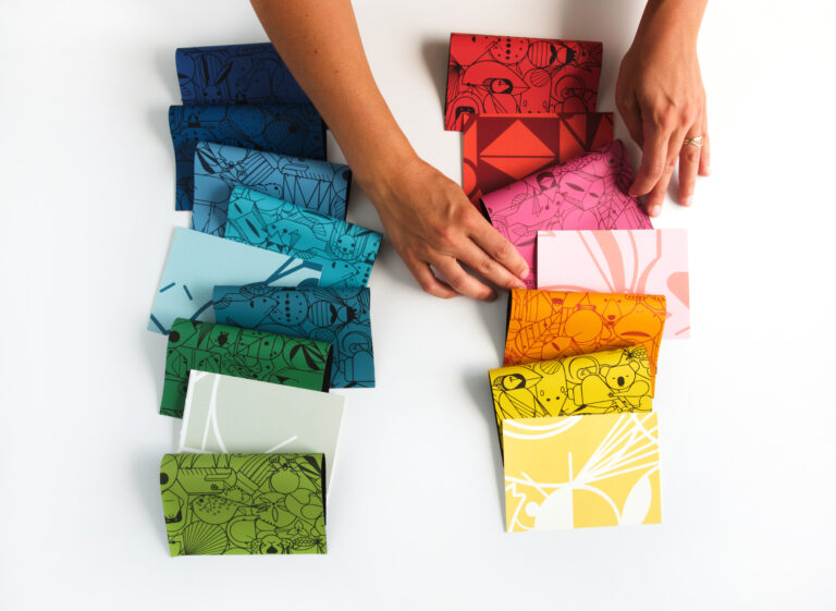 A pair of hands arranges rows of samples of Beguiled by the Wild Upholstery and Beguiled by the Wild Walls.