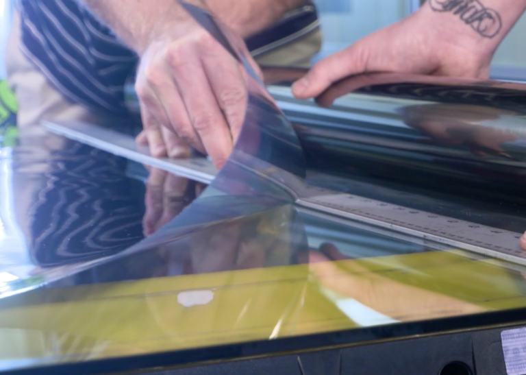 Hands cutting a roll of casper cloaking film.