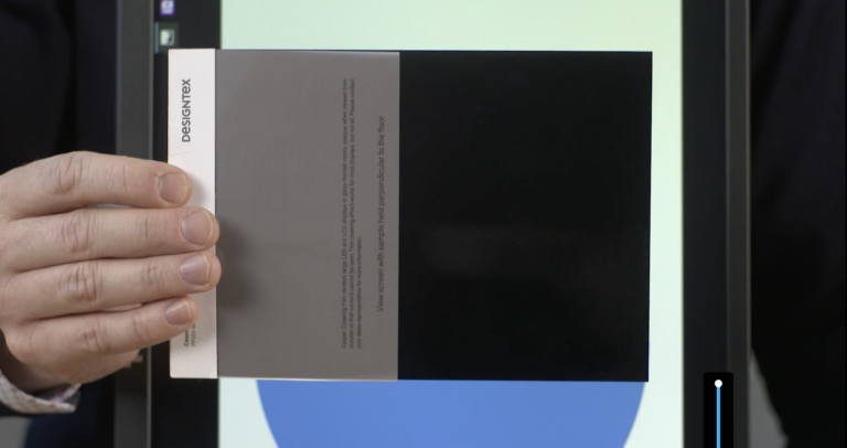 A sample of Casper is in someone's hand and they are testing compatibility with the monitor.